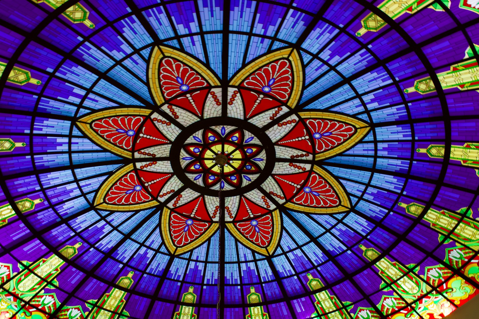 A colorful stained glass ceiling with a flower design